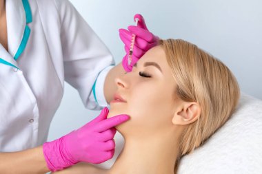 Doktor burundaki küçük kamburu düzeltiyor. Estetik cerrah, klinikte genç sarışın bir kadının burnunu burun estetiği yapar. Kadın kozmetolojisi kavramı.