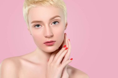 Kısa sarı saçlı, güzel makyajlı ve pembe arka planda sağlıklı ciltli güzel bir kadının portresi. Makyaj ve kozmetoloji kavramı.