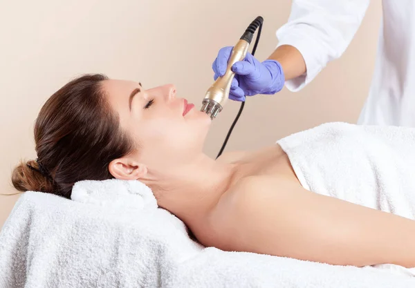 Beautician does the procedure rf-lifting on face and neck. Rf lifting procedure in a beauty salon. Cosmetology and professional skin care.