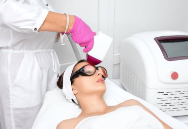 Elos epilasyon tüy çıkarma prosedürü bir kadının yüzünde. Güzellik uzmanı bir güzellik salonunda alnına lazer gençleştirme yapıyor. Yüz bakımı. Donanım ipl kozmetolojisi