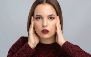 Güzel makyajlı esmer kız, temiz tenli, uzun saçlı, bordo kazaklı. Yeni yıl konsepti