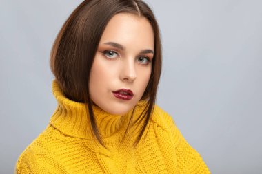 Güzel makyajlı esmer kız, temiz tenli, sarı kazaklı uzun saçlı. Yeni yıl konsepti