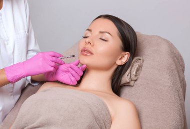 Kozmetik uzmanı, güzellik salonundaki güzel bir kadının yüzünde ve çenesinde kırışıklık önleyici terapi uygular. Kozmetoloji ve profesyonel cilt bakımı.