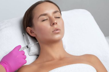 Kozmetik uzmanı, bir kadının çenesinde, yanaklarında ve boynunda çift çeneye karşı yağ yakmak için lipolitik enjeksiyon yapar. Güzellik salonunda kadın estetiği. Kozmetoloji konsepti..