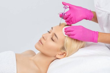 Kozmetik uzmanı güzel bir kadının yüzüne kırışıklık önleyici iğneler yapıyor. Güzellik salonunda kadın estetiği..