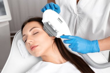 Elos epilasyon tüy çıkarma prosedürü bir kadının yüzünde. Güzellik uzmanı bir güzellik salonunda lazer gençleştirme yapıyor. Yüz bakımı. Donanım ipl kozmetolojisi
