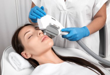 Elos epilasyon tüy çıkarma prosedürü bir kadının yüzünde. Güzellik uzmanı bir güzellik salonunda lazer gençleştirme yapıyor. Yüz bakımı. Donanım ipl kozmetolojisi
