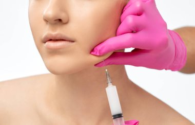 Cosmetologist makes lipolytic injections to burn fat on the chin, cheeks and neck of a woman against double chin. Female aesthetic cosmetology in a beauty salon.Cosmetology concept. clipart