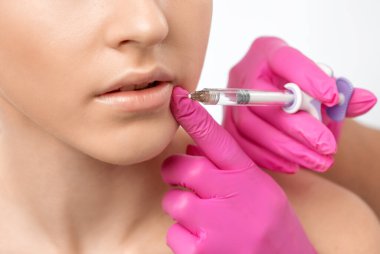 Kozmetik uzmanı, güzel bir kadının burun kıvrımlarında dudak büyütme ve kırışıklık önleyici iğneler yapar. Güzellik salonunda kadın kozmetolojisi.