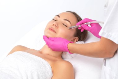 Kozmetik uzmanı yüzünde sivilce ve göz kenarındaki siyah noktalara karşı mikro dermabrüksiyon uygular. Güzellik salonunda kadın kozmetolojisi.