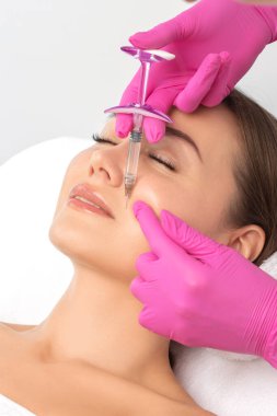 Kozmetik uzmanı, güzel sarışın bir kadının yüzüne kırışıklık önleyici iğneler yapıyor. Güzellik salonunda kadın estetiği..