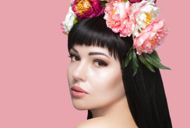 Güzel, uzun saçlı ve makyajlı mutlu bir kadının portresi. Onun kafasında bir çiçek çelengi var. Kozmetoloji cilt bakımı ve makyaj.