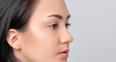 Permanent make-up for eyebrows of beautiful woman with thick brows in beauty salon. Closeup beautician doing tattooing eyebrow. Professional makeup and cosmetology skin care.