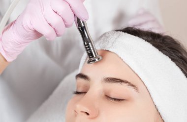 Kozmetik uzmanı yüzünde sivilce ve göz kenarındaki siyah noktalara karşı mikro dermabrüksiyon uygular. Güzellik salonunda kadın kozmetolojisi.