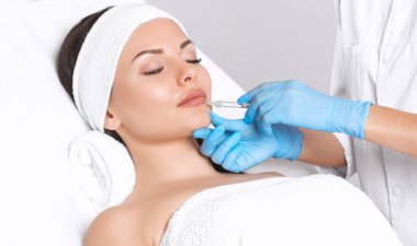 Kozmetik uzmanı, güzel bir kadının burun kıvrımlarında dudak büyütme ve kırışıklık önleyici iğneler yapar. Güzellik salonunda kadın kozmetolojisi.