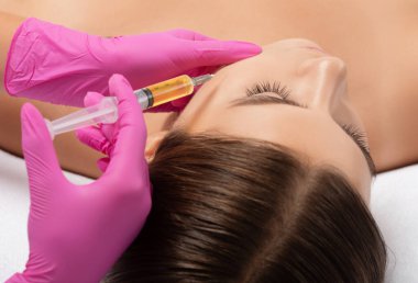 Kozmetik uzmanı güzellik salonunda güzel bir kadının yüzü üzerinde terapi uygular. Kozmetoloji kavramı.