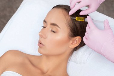 Kozmetik uzmanı kuaförde saç dökülmesine ve kepek önleyici bir kadına karşı terapi uygular. Kozmetoloji kavramı.