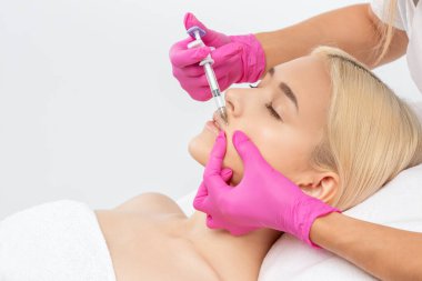 Kozmetik uzmanı güzel bir kadının yüzüne kırışıklık önleyici iğneler yapıyor. Güzellik salonunda kadın estetiği..