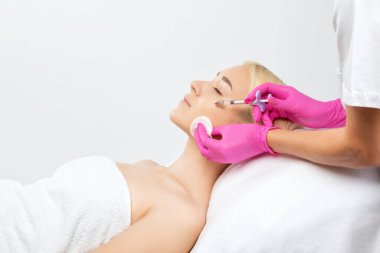 Kozmetik uzmanı güzel bir kadının yüzüne kırışıklık önleyici iğneler yapıyor. Güzellik salonunda kadın estetiği..