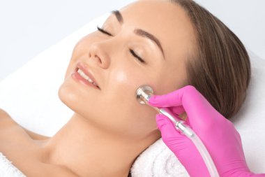 Kozmetik uzmanı yüzünde sivilce ve göz kenarındaki siyah noktalara karşı mikro dermabrüksiyon uygular. Güzellik salonunda kadın kozmetolojisi.