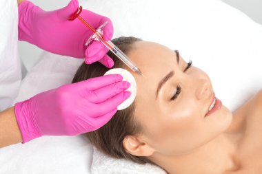 Kozmetik uzmanı güzel bir kadının yüzüne kırışıklık önleyici iğneler yapıyor. Güzellik salonunda kadın estetiği..