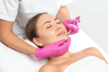 Kozmetik uzmanı güzel bir kadının yüzüne kırışıklık önleyici iğneler yapıyor. Güzellik salonunda kadın estetiği..