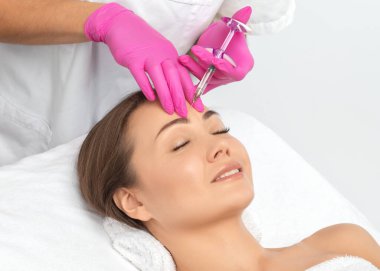 Kozmetik uzmanı güzel bir kadının yüzüne kırışıklık önleyici iğneler yapıyor. Güzellik salonunda kadın estetiği..