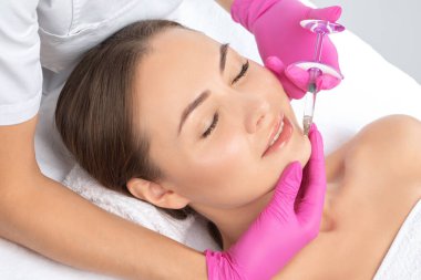 Kozmetik uzmanı güzel bir kadının yüzüne kırışıklık önleyici iğneler yapıyor. Güzellik salonunda kadın estetiği..