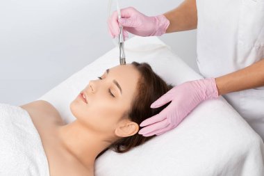 Kozmetik uzmanı, güzellik salonundaki güzel bir kızın yüzünün mikro cilt bakımını yapıyor. Kozmetoloji ve profesyonel cilt bakımı..