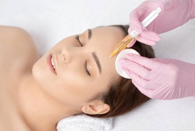 Cosmetologist does prp therapy on the face of a beautiful woman in a beauty salon. Cosmetology concept. clipart