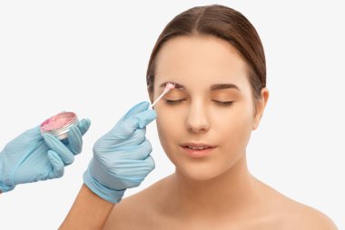 Makyaj sanatçısı kaşlar için beyaz kalemle işaretler yapar ve kaşları boyar. Profesyonel makyaj ve yüz bakımı.