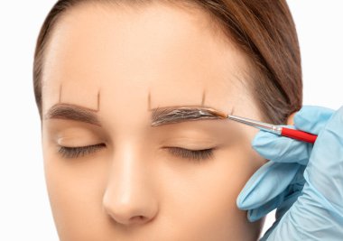 Makyaj sanatçısı kaşlar için beyaz kalemle işaretler yapar ve kaşları boyar. Profesyonel makyaj ve yüz bakımı.