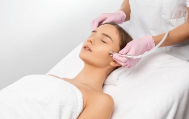 Kozmetik uzmanı, güzellik salonundaki güzel bir kızın yüzünün mikro cilt bakımını yapıyor. Kozmetoloji ve profesyonel cilt bakımı..