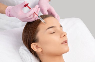 Kozmetik uzmanı güzel bir kadının yüzüne kırışıklık önleyici iğneler yapıyor. Güzellik salonunda kadın estetiği..