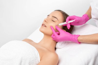 Kozmetik uzmanı, bir kadının çenesinde, yanaklarında ve boynunda çift çeneye karşı yağ yakmak için lipolitik enjeksiyon yapar. Güzellik salonunda kadın estetiği. Kozmetoloji konsepti..