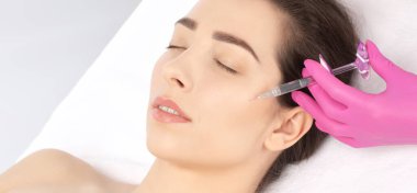 Kozmetik uzmanı güzel bir kadının yüzüne kırışıklık önleyici iğneler yapıyor. Güzellik salonunda kadın estetiği..