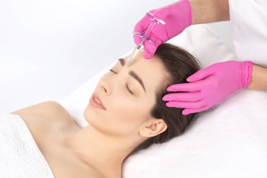 Kozmetik uzmanı güzel bir kadının yüzüne kırışıklık önleyici iğneler yapıyor. Güzellik salonunda kadın estetiği..