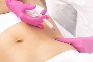 Estetik kozmetik doktorları kalçalarında ve kalçalarında vücut yağlarını yakmak için lipolitik enjeksiyonlar yaparlar. Güzellik salonunda kadın estetiği..