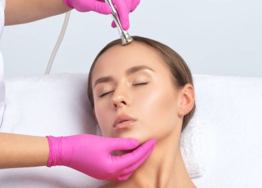 Kozmetik uzmanı, güzellik salonundaki güzel bir kızın yüzünün mikro cilt bakımını yapıyor. Kozmetoloji ve profesyonel cilt bakımı..