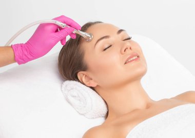 Kozmetik uzmanı yüzünde sivilce ve göz kenarındaki siyah noktalara karşı mikro dermabrüksiyon uygular. Güzellik salonunda kadın kozmetolojisi.