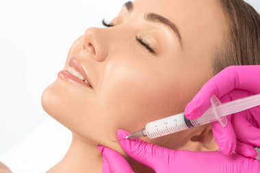 Kozmetik uzmanı, bir kadının çenesinde, yanaklarında ve boynunda çift çeneye karşı yağ yakmak için lipolitik enjeksiyon yapar. Güzellik salonunda kadın estetiği. Kozmetoloji konsepti..