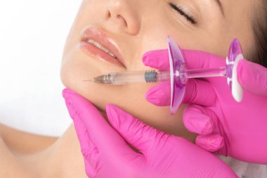 Kozmetik uzmanı güzel bir kadının yüzüne kırışıklık önleyici iğneler yapıyor. Güzellik salonunda kadın estetiği..