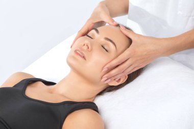 Masör, kaplıcadaki genç ve güzel bir kadının yüzüne, boynuna, omuzlarına ve köprücük kemiklerine rahatlatıcı bir masaj yapar. Kozmetoloji ve masaj konsepti.