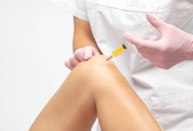 Yaralanmadan sonra bir hastanın dizinde kök hücre tedavisi yapan bir doktor. Diz ağrısını trombosit zengini plazma enjeksiyonuyla tedavi ediyorum. Eklem iltihabı ve osteoartrit tedavisi. Tıbbi ve kozmetik konsepti..