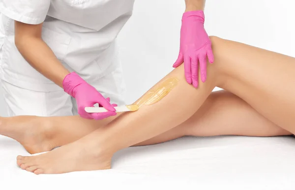 Stock image A beautician makes a sugar paste depilation of a woman's legs in a beauty salon. Female aesthetic cosmetology.