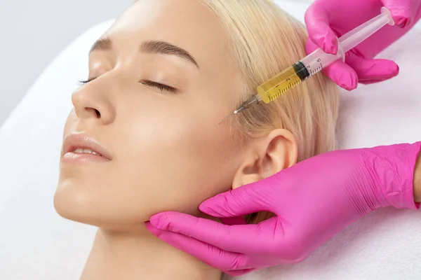 A doctor of aesthetic cosmetology makes lipolytic injections to burn body fat on womans stomach and body. Female aesthetic cosmetology in a beauty salon.