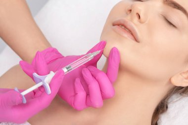 Kozmetik uzmanı güzel bir kadının yüzüne kırışıklık önleyici iğneler yapıyor. Güzellik salonunda kadın estetiği..