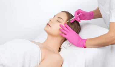 Kozmetik uzmanı güzel bir kadının yüzüne kırışıklık önleyici iğneler yapıyor. Güzellik salonunda kadın estetiği..