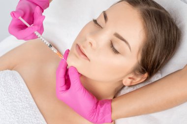 Kozmetik uzmanı güzel bir kadının yüzüne kırışıklık önleyici iğneler yapıyor. Güzellik salonunda kadın estetiği..