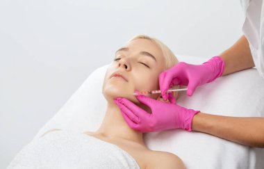 Kozmetik uzmanı güzel bir kadının yüzüne kırışıklık önleyici iğneler yapıyor. Güzellik salonunda kadın estetiği..